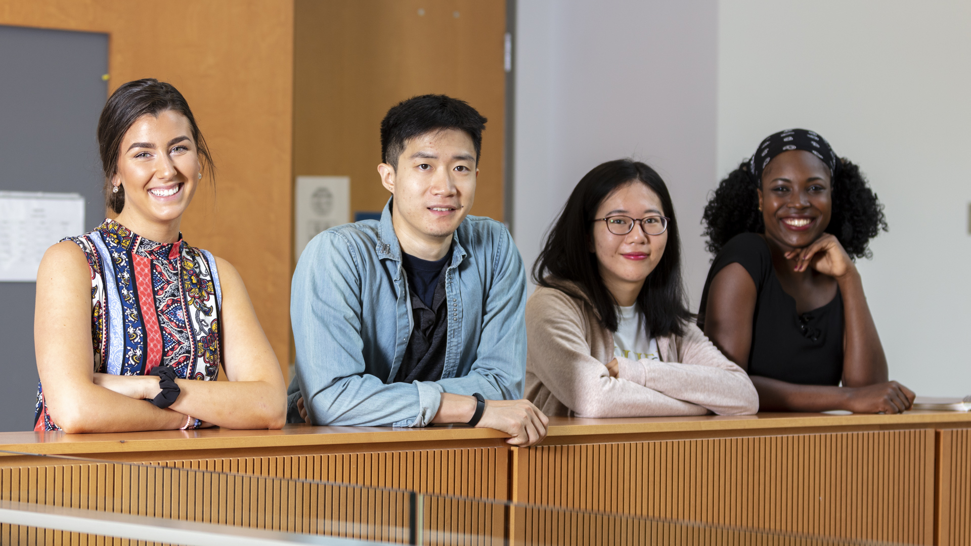 four international students leaning on wall posing